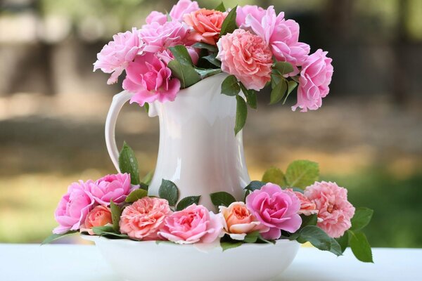 Pichet avec des fleurs roses sur une assiette