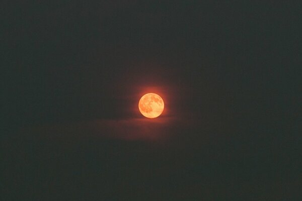 La Luna en el cielo en las nubes y la oscuridad alrededor