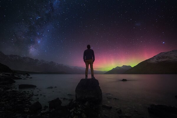 Mann vor dem Hintergrund der Nordlichter und des Sternenhimmels