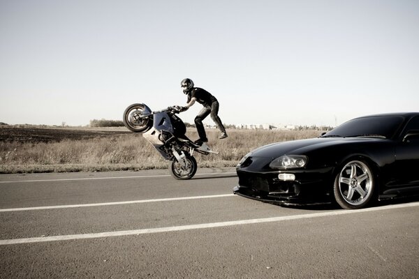 Motociclista esegue una prodezza sulla strada accanto alla macchina