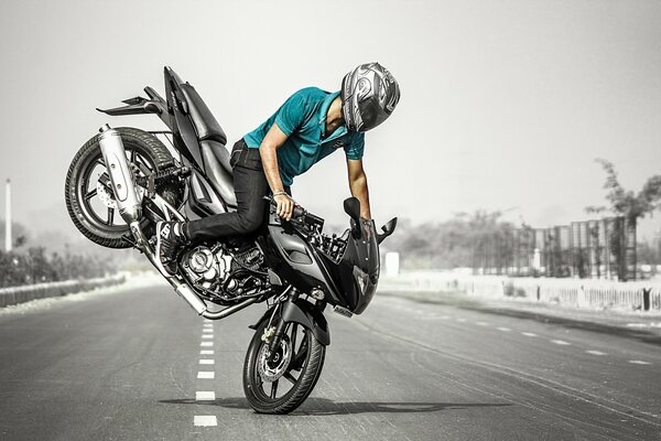 Un motociclista hace un truco peligroso en una motocicleta negra en medio de la carretera