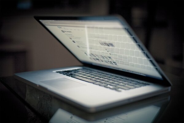 A half-open, switched-on MacBook on the table