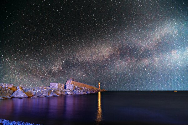 Faro de la bahía ilumina el cielo de agua todo en las estrellas