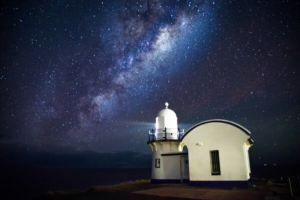 Un faro junto al mar y un cielo estrellado claro