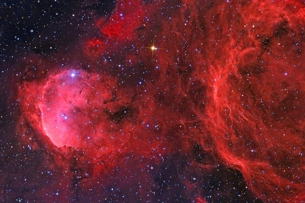 A scarlet nebula with blue and yellow glow against the background of black stellar space