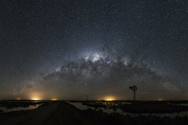 Paesaggio notturno con luci sotto il cielo cosmico