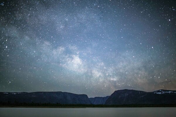 Night lake brightening the shore with a starry sky