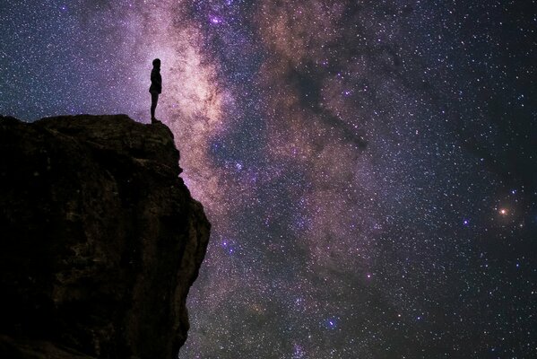 Silhouette on a rock against the background of the starry sky