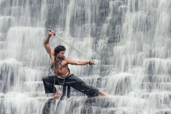 Un uomo con una spada su una cascata