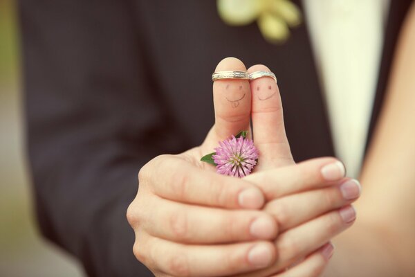 The bride and groom drew faces on their fingers and hold hands