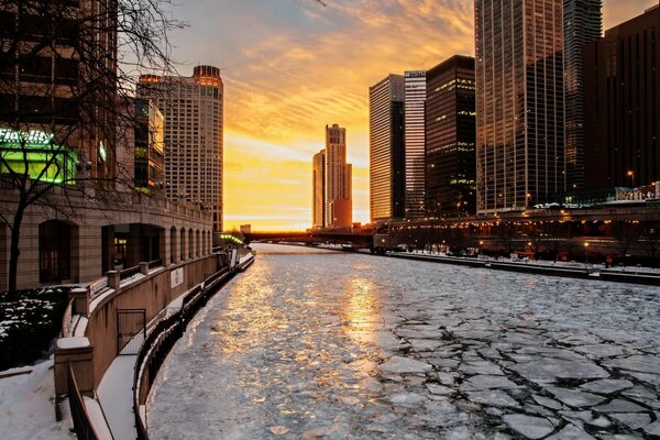 Cracked ice on the river in the rays of the city sunset