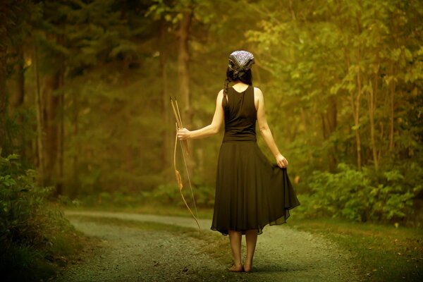 Chica con arco y flecha en el bosque