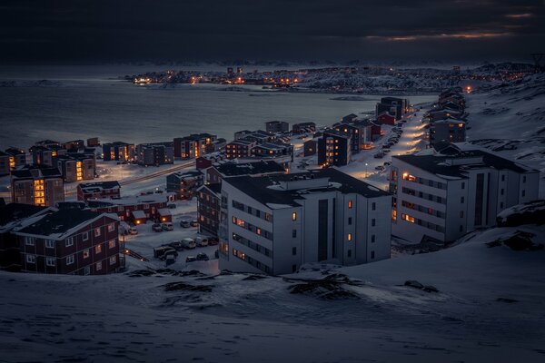 Snow-covered evening city on the shore of the bay