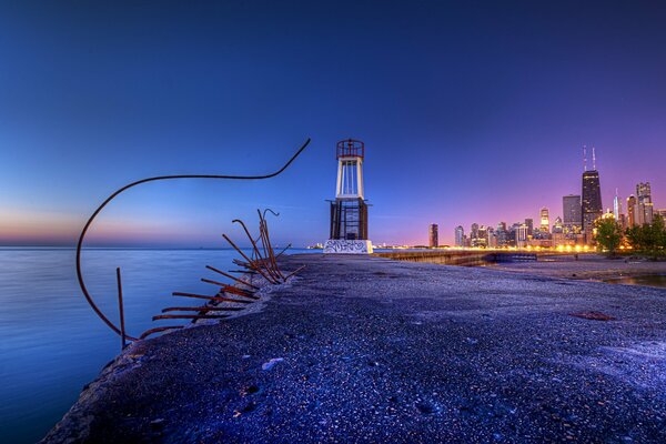 Breakwater with protruding fittings on the background of the night city