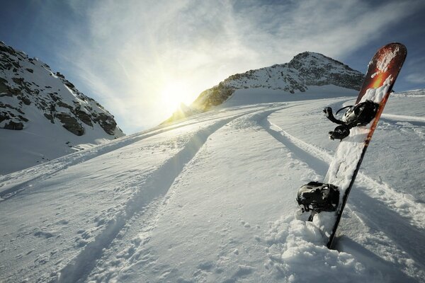 Board in the snow on the background of the mountain and the sun