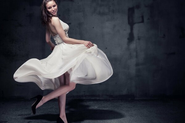 Modelo en un hermoso vestido de parapeto en una habitación oscura