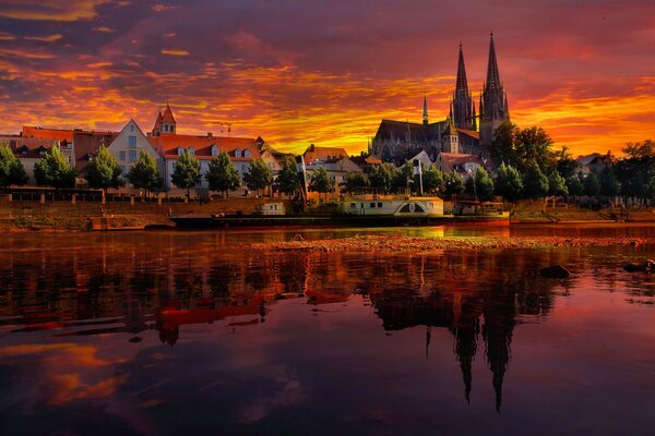 Sonnenuntergang und brennender Himmel in Regensburg, Deutschland. Reflexion der Stadt und der Kathedrale im Fluss