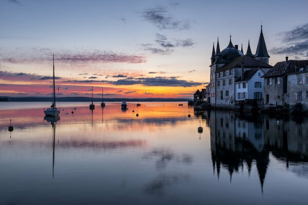 Schloss am Seeufer am Abend. Reflexion des Sonnenuntergangs im See