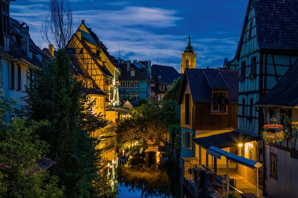 Quiet night streets of France. The light of the lanterns is reflected in the water channel
