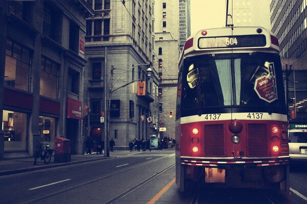 A red tram is standing in the middle of the road