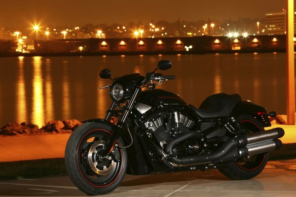 Motocicleta Harley Davidson negra en el fondo de la ciudad de la noche