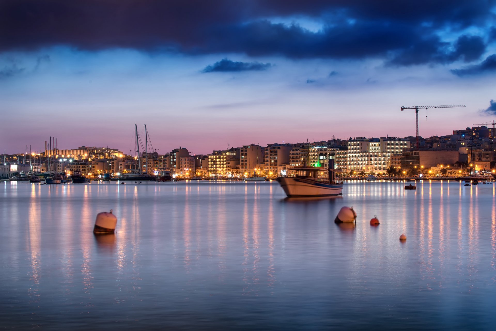 malta sliema miasto domy oświetlenie wybrzeże morze boje łodzie wieczór różowy niebieski niebo chmury