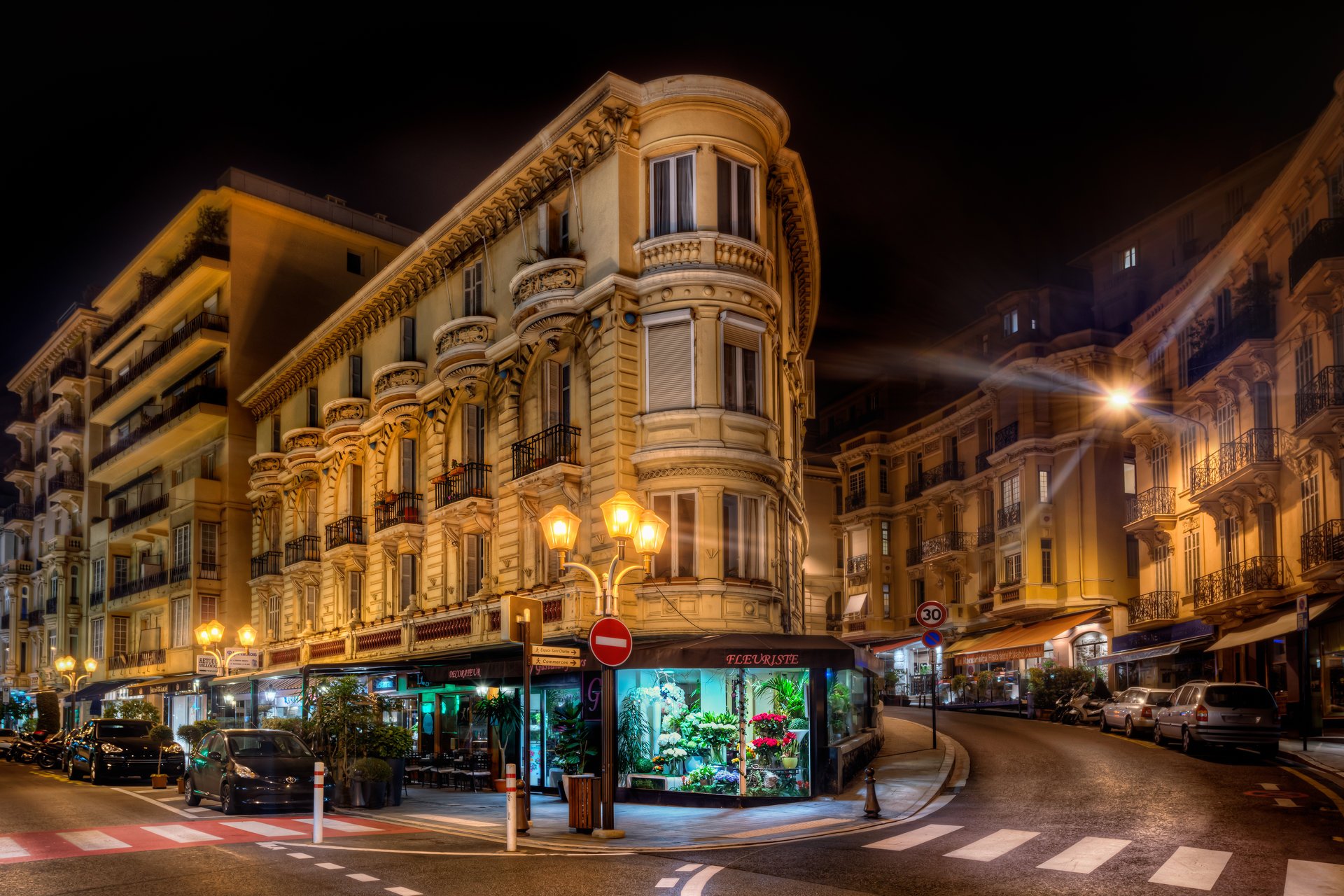 jacob surland monaco ville de nuit éclairage lanternes lumière rayons bâtiments rue tourner voitures motos parking trottoir vitrine rétro-éclairage fleuriste