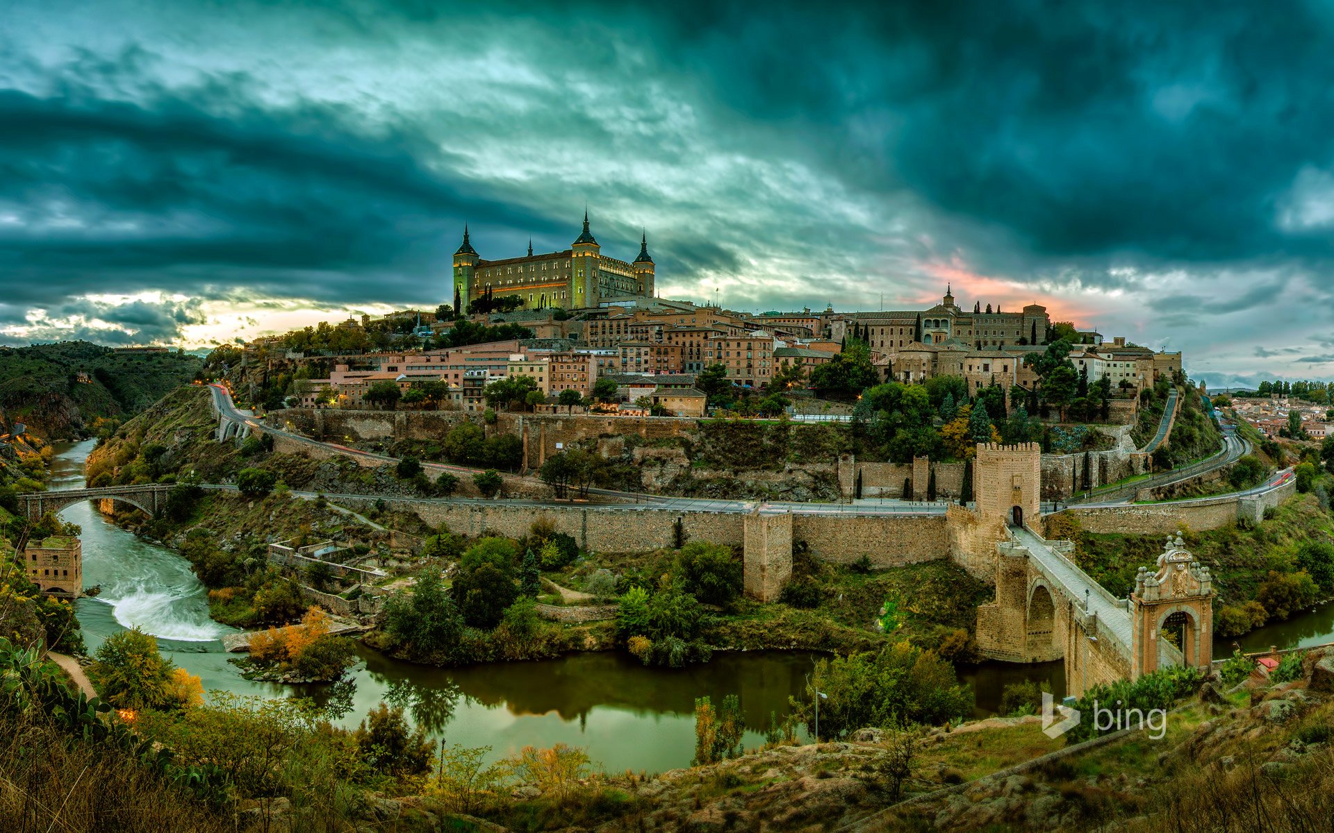 toledo spagna paesaggio collina castello case torre alberi cielo nuvole tramonto fiume ponte