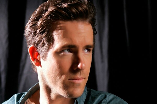 Ryan Reynolds poses on a dark background