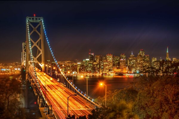 A bright night panorama of city lights - with a bridge, a river and high-rise buildings