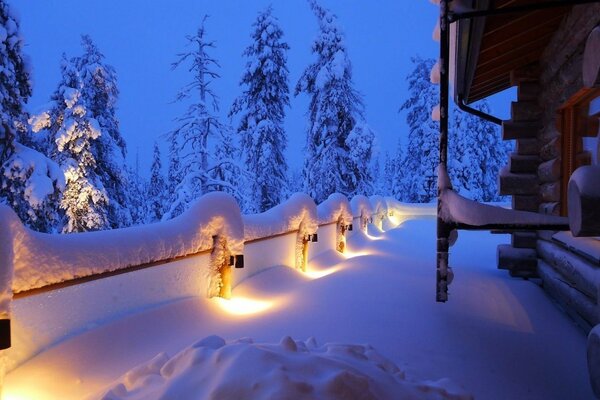 Holzhaus mit Schnee auf dem Hintergrund des Waldes bedeckt