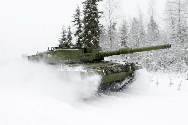 The tank breaks through the virgin snow on the background of the forest