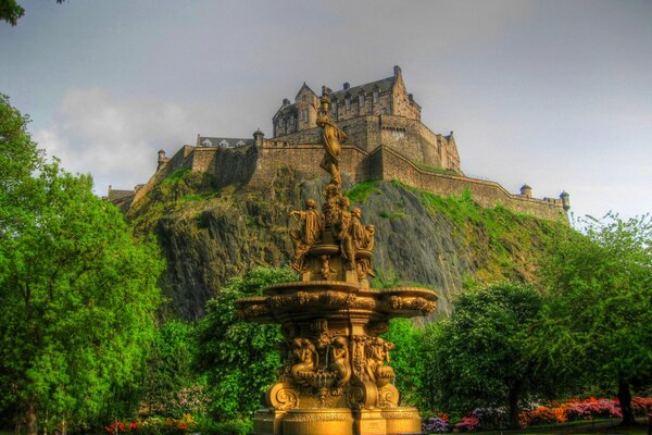 Fountain on the background of trees. A mountain covered with greenery