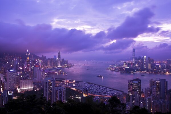 Port Wiktorii w odcieniach bzu. Zatoka Port Wiktorii. Krajobraz Hongkong, Chiny. Oświetlenie nocnego miasta Hongkong. Widok na drapacze chmur pod otwartym nocnym niebem