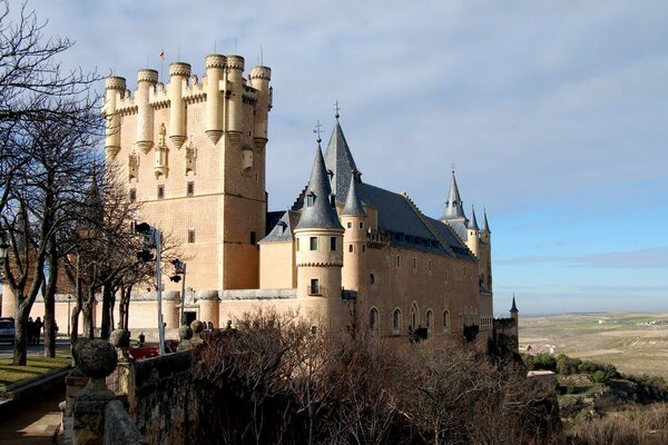 Hermoso castillo con árboles sin hojas contra el cielo azul