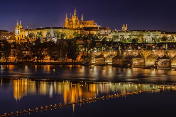 The night city of Prague is reflected in the Vltava River