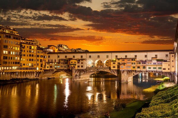 Italienische Stadt über dem Fluss mit Sonnenuntergang