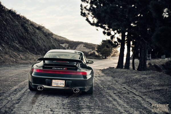 Porsche nera guida lungo la strada