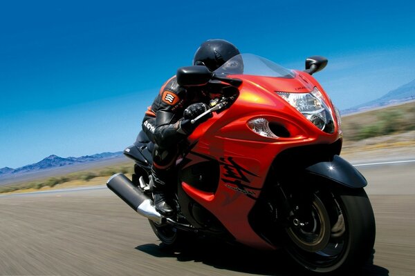 Moto rossa Suzuki. Velocità. Strada. Cielo blu chiaro