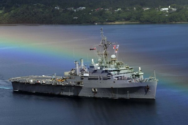 A warship at sea with a multicolored rainbow shadow