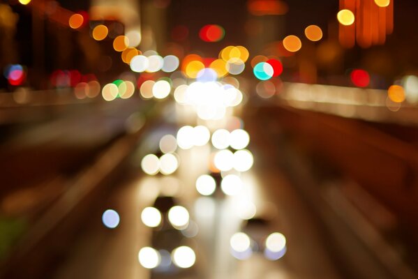 Los reflejos de las luces de los coches de los faros en la calle de noche