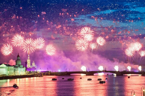 Nachtstadt vor dem Hintergrund von bunten Feuerwerkskörpern, die sich im Wasser widerspiegeln