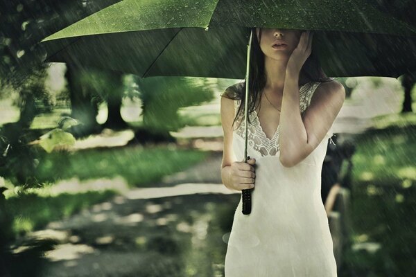 Belleza modelo en la lluvia bajo un paraguas
