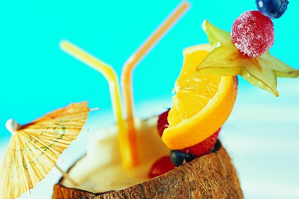 Cocktail tropicale in cocco con ombrello e frutta su uno spiedino