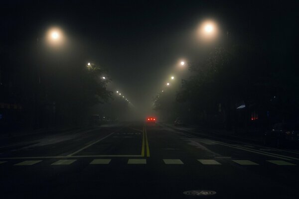 Auto di passaggio nella nebbia notturna