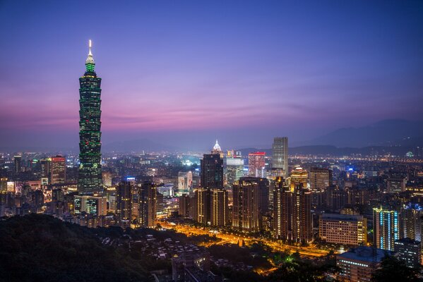 Die Gebäude der chinesischen Stadt spiegeln sich am Abend im violetten Himmel wider