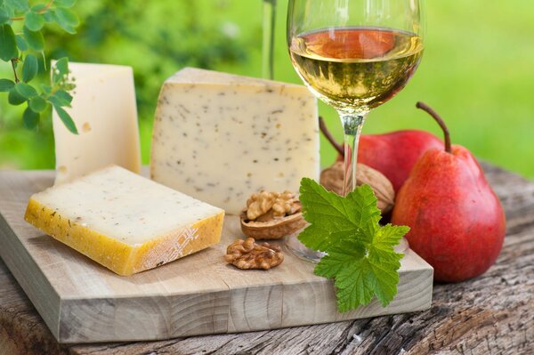 Fromage sur une planche à découper avec du vin blanc et des poires