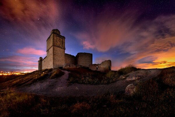 Kamienny zamek na wzgórzu pod fantastycznym niebem