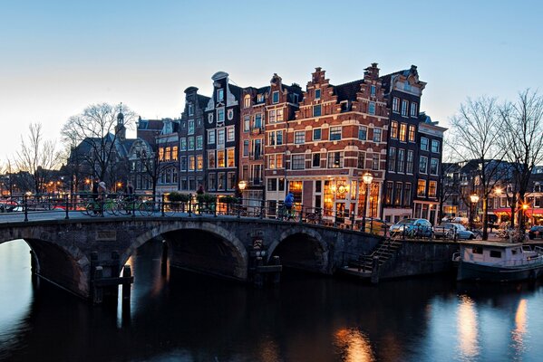 Most na rzece w Amsterdamie oświetlony wieczornymi latarniami