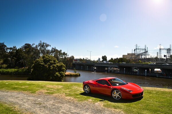 Czerwone Ferrari stoi na trawie w pobliżu rzeki
